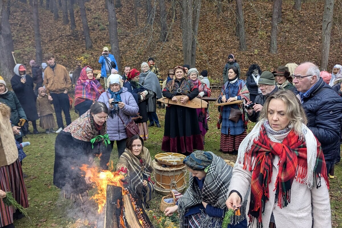 Besucher in traditioneller lettischer Volkstracht am Lagerfeuer zur Mārtiņdiena im Freilichtmuseum, Riga.