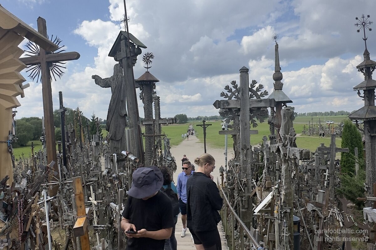 Berg der Kreuze (Kryžių kalnas) bei Šiauliai, Litauen — Holzsteg mit der stehenden Jesus-Statue und Kreuzen in alle Richtungen.