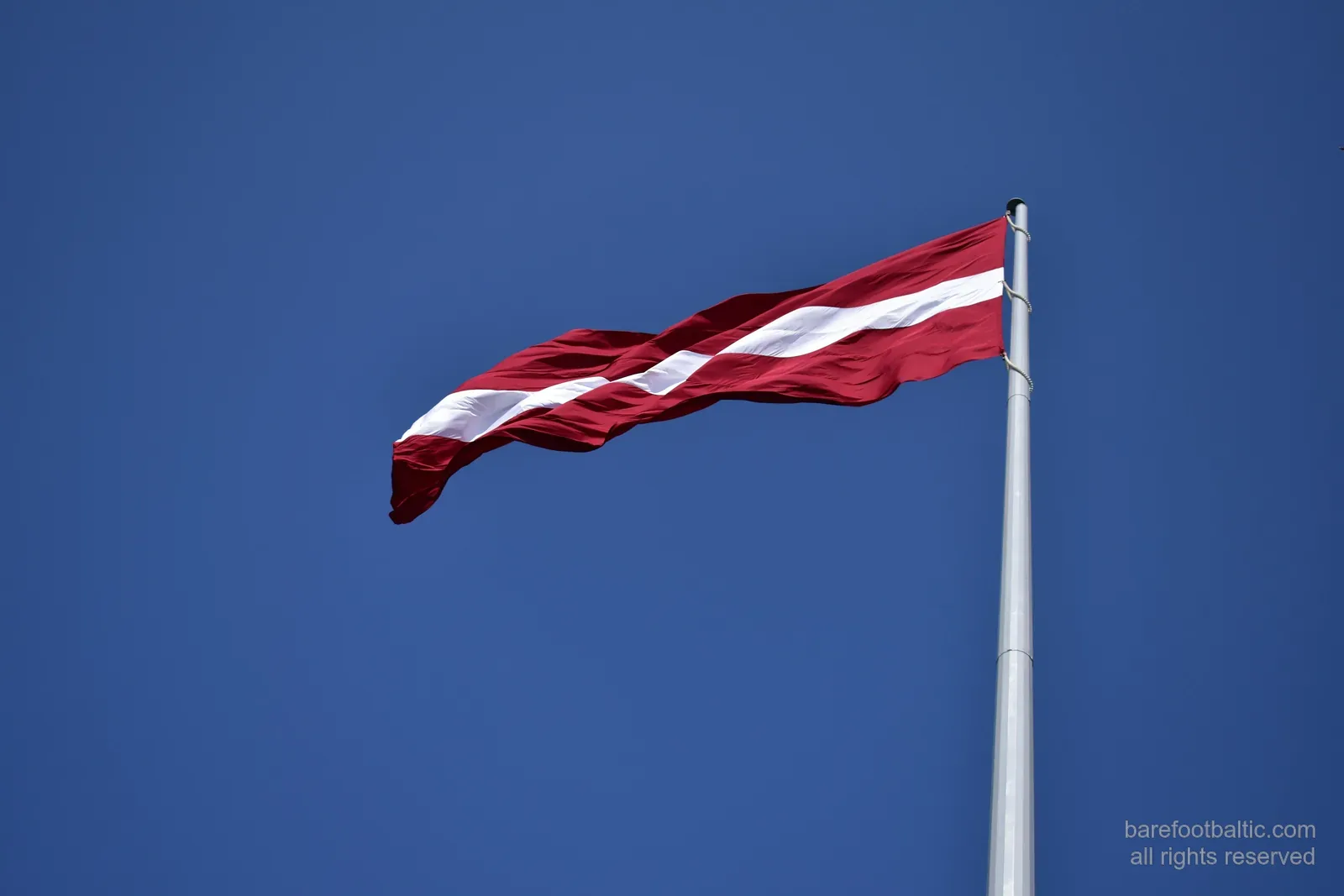 Die lettische Flagge vor blauem Himmel
