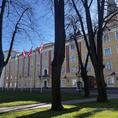 Pils laukums im Frühling mit Burgflaggen zwischen kahlen Bäumen, Riga, Lettland