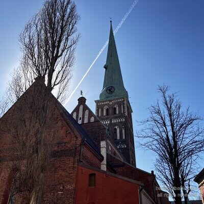 Der Spitzturm der Jakobskathedrale von unten mit einem Kondensstreifen am Himmel, Riga, Lettland
