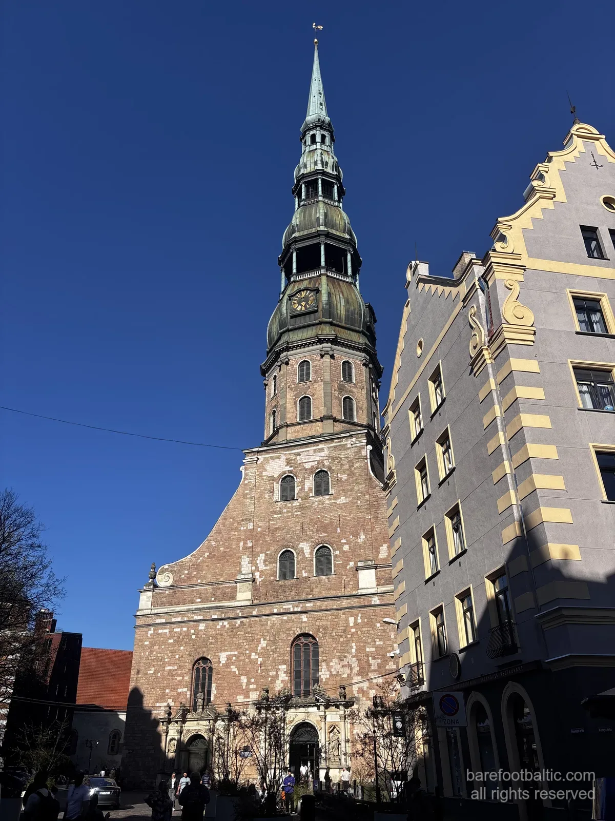 Die Petrikirche (Sv. Pētera baznīca) mit ihrem hohen gr&uuml;nen Turmhelm vor blauem Himmel in der Rigaer Altstadt, Lettland.