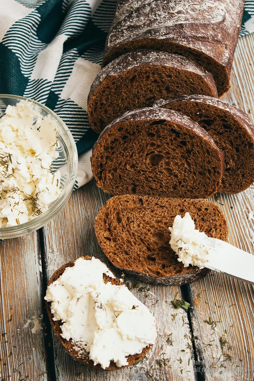 Aufgeschnittenes rupjmaize — dunkles Roggenbrot — mit einer Schale biezpiens (Quark), bestreut mit Dill