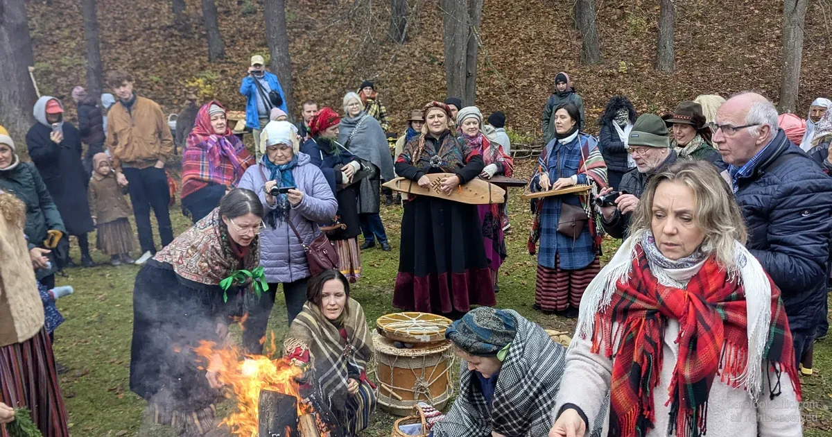 Besucher in Volkstracht am Mārtiņdiena-Lagerfeuer im lettischen Ethnographischen Freilichtmuseum, Riga.